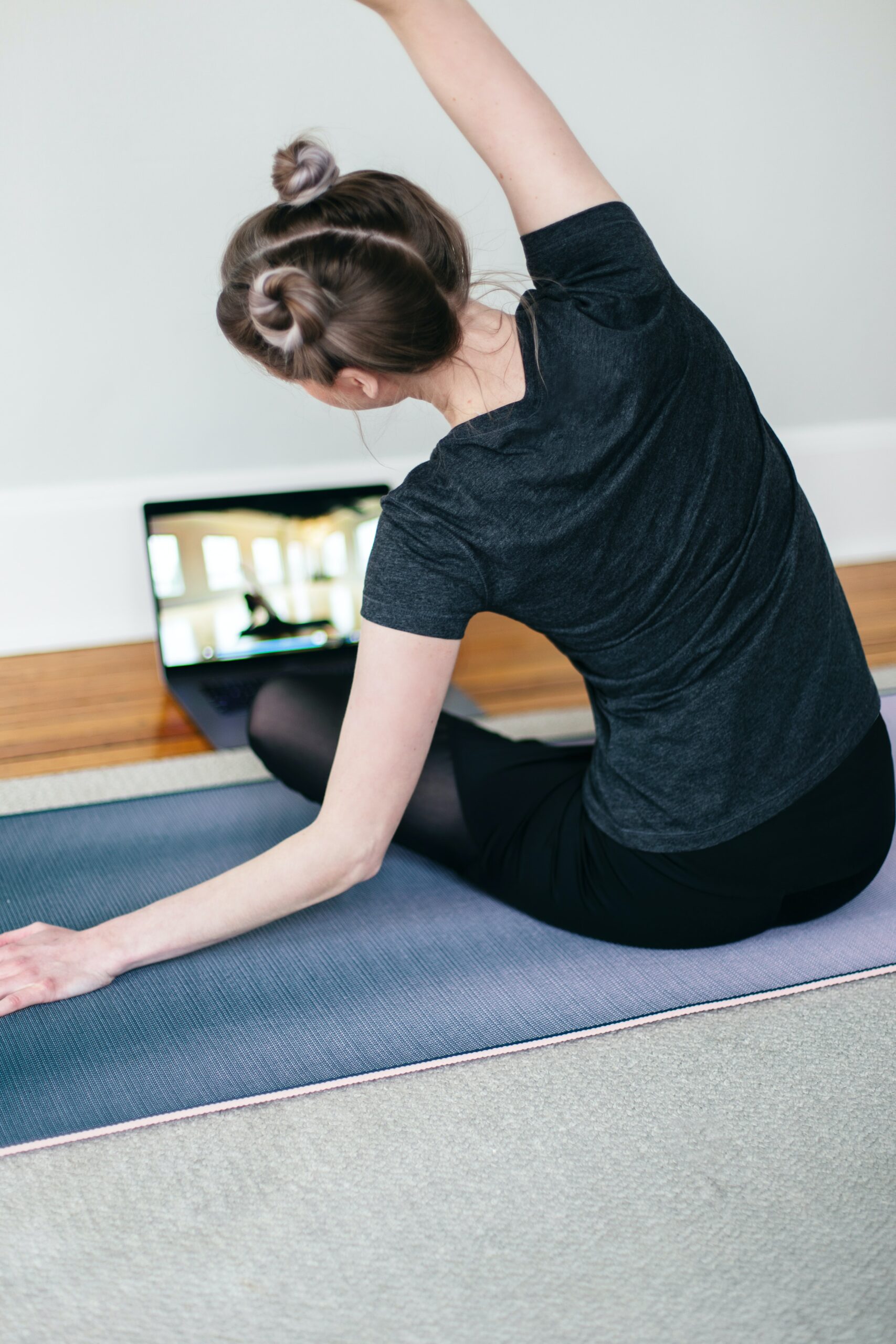 Girl stretching in front of computer playing a yoga video