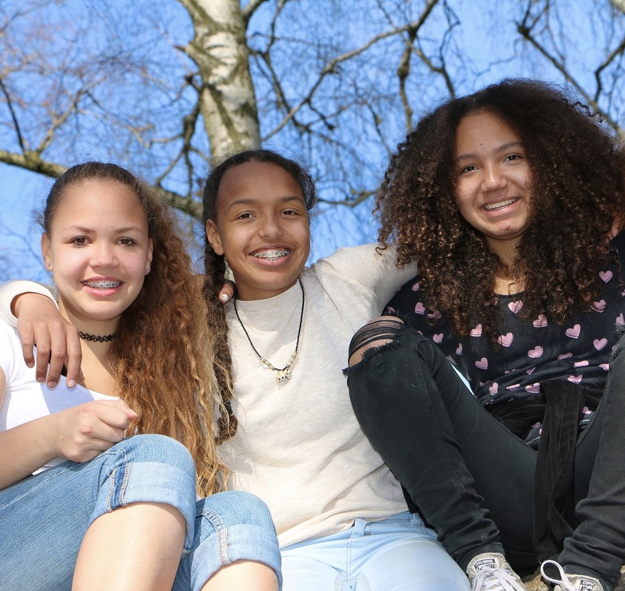 Three girls sitting together, arms wrapped around each other