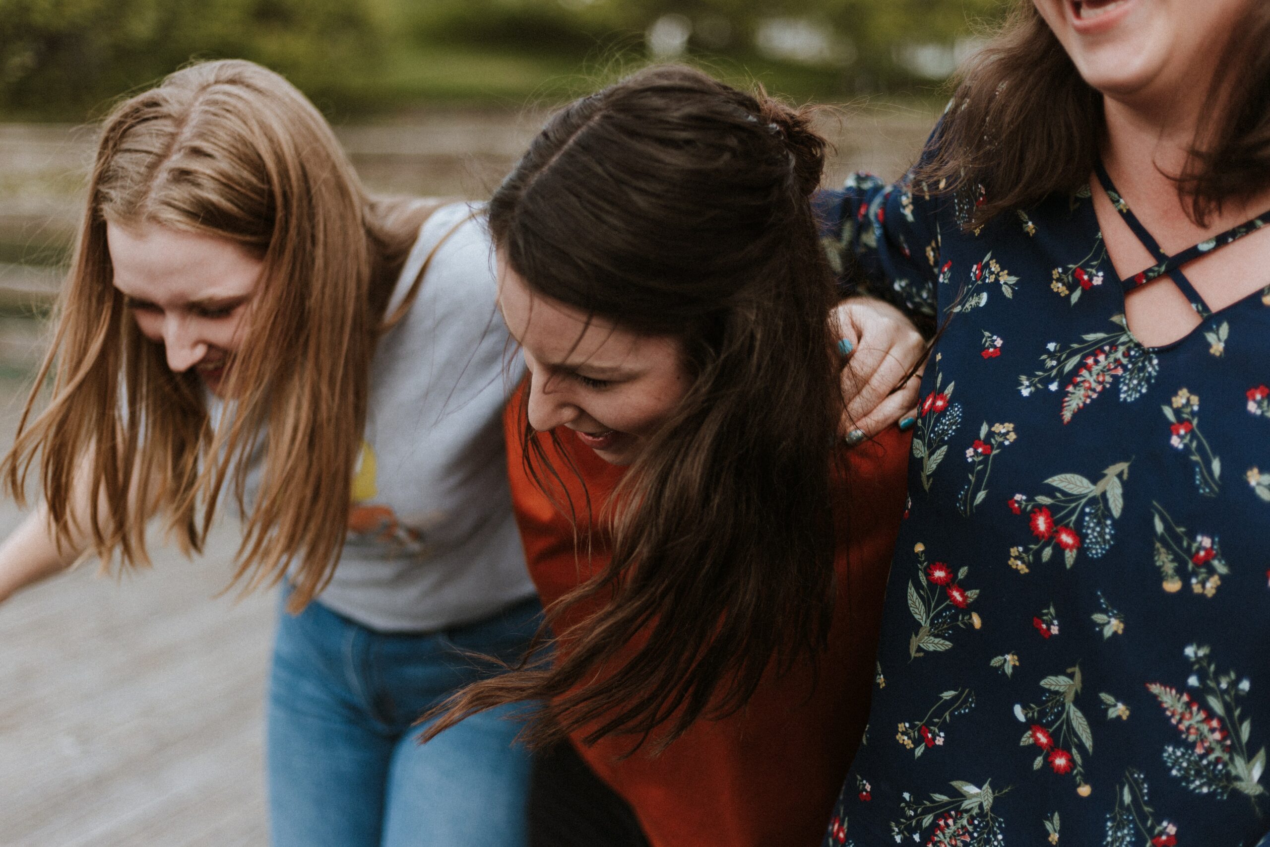 Two girls bent over, walking together and smiling